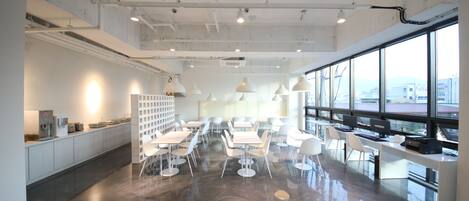A spacious, modern office with a polished floor, white furniture, and large windows offering a view of the city.