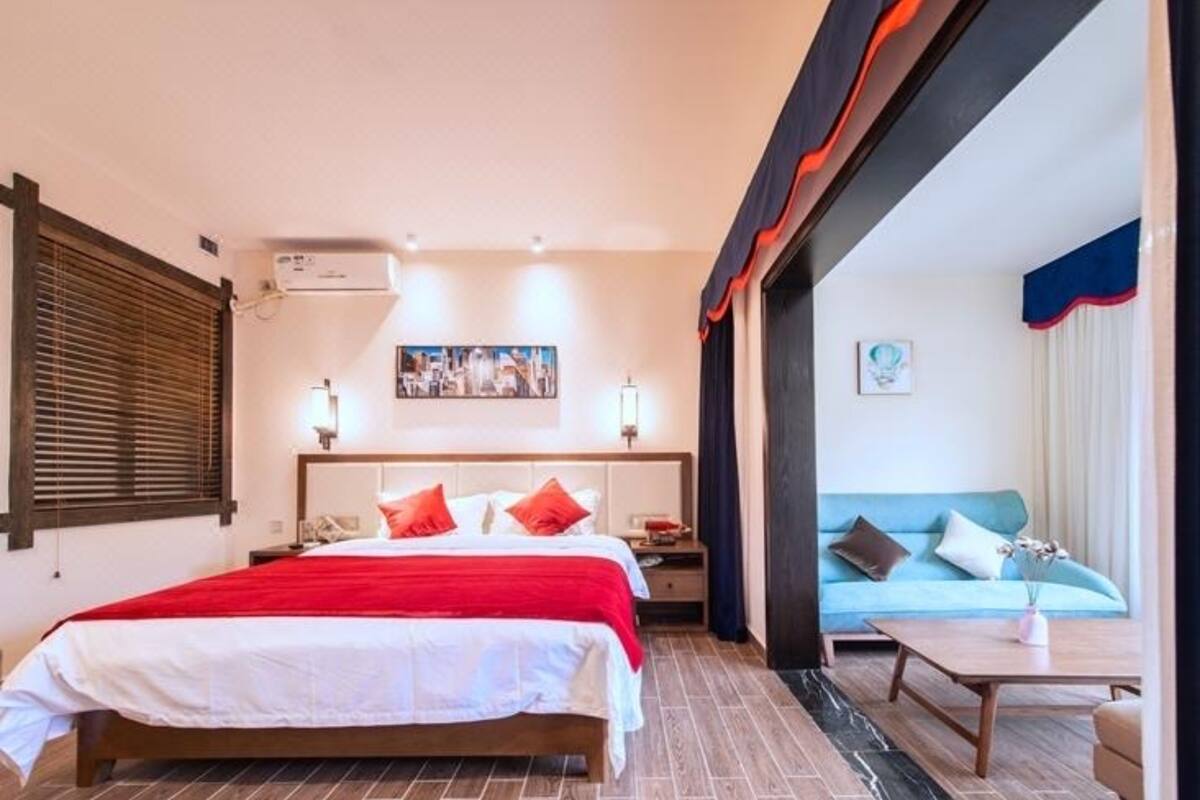 Une chambre d’hôtel comprenant un lit, des tables de chevet, une commode, un canapé et une table basse.