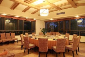 Comedor con mesa redonda, sillas de mimbre y ventanas amplias.