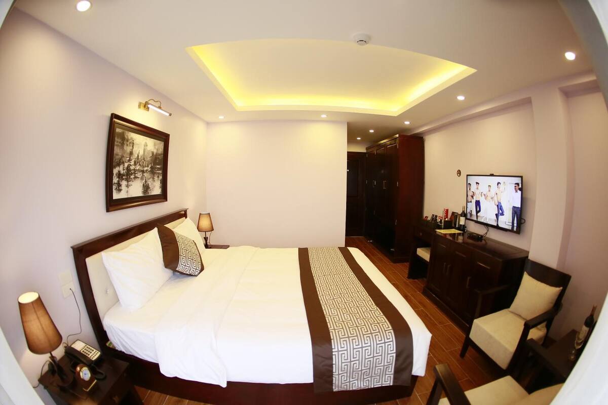 Een hotelkamer met een groot bed, een bureau met een televisie, en een badkamer op de achtergrond.