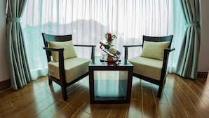 A room with two chairs, a small table, and a window with curtains. - Le Bordeaux Sapa Hotel (Sa Pa)