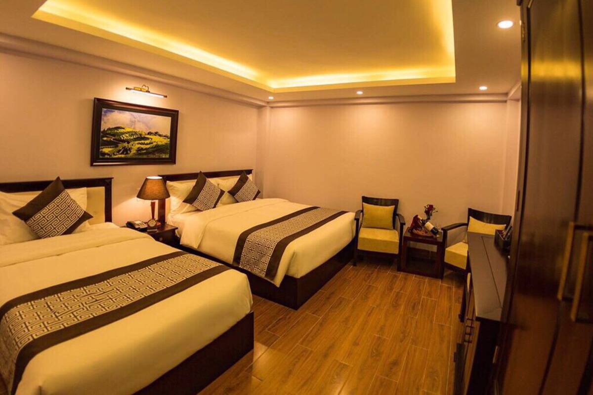 Een hotelkamer met twee bedden, een zithoekje en een koelkast.
