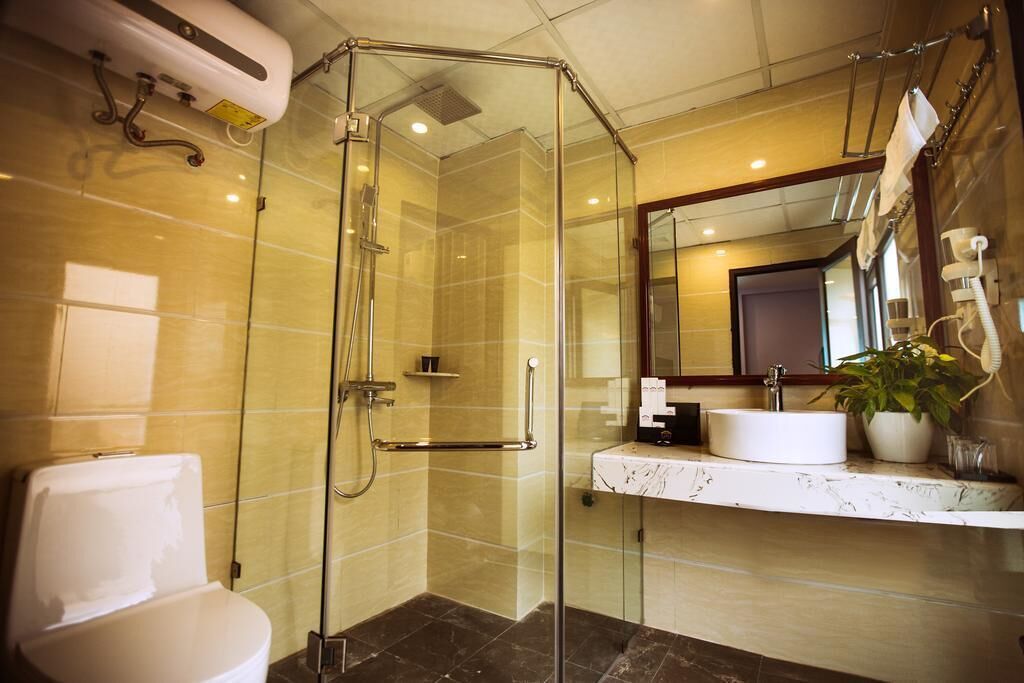 A modern bathroom with a glass-enclosed shower, a white toilet, and a marble sink with a mirror above.