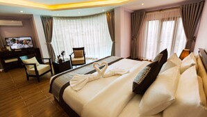 A hotel room with a large bed, a desk with a chair, a television, and curtains. - Le Bordeaux Sapa Hotel (Sa Pa)