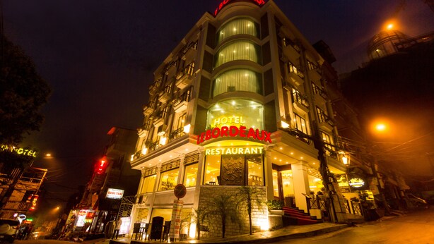 A hotel with a restaurant on the ground floor, featuring a prominent sign and a staircase leading to the entrance. - Le Bordeaux Sapa Hotel (Sa Pa)