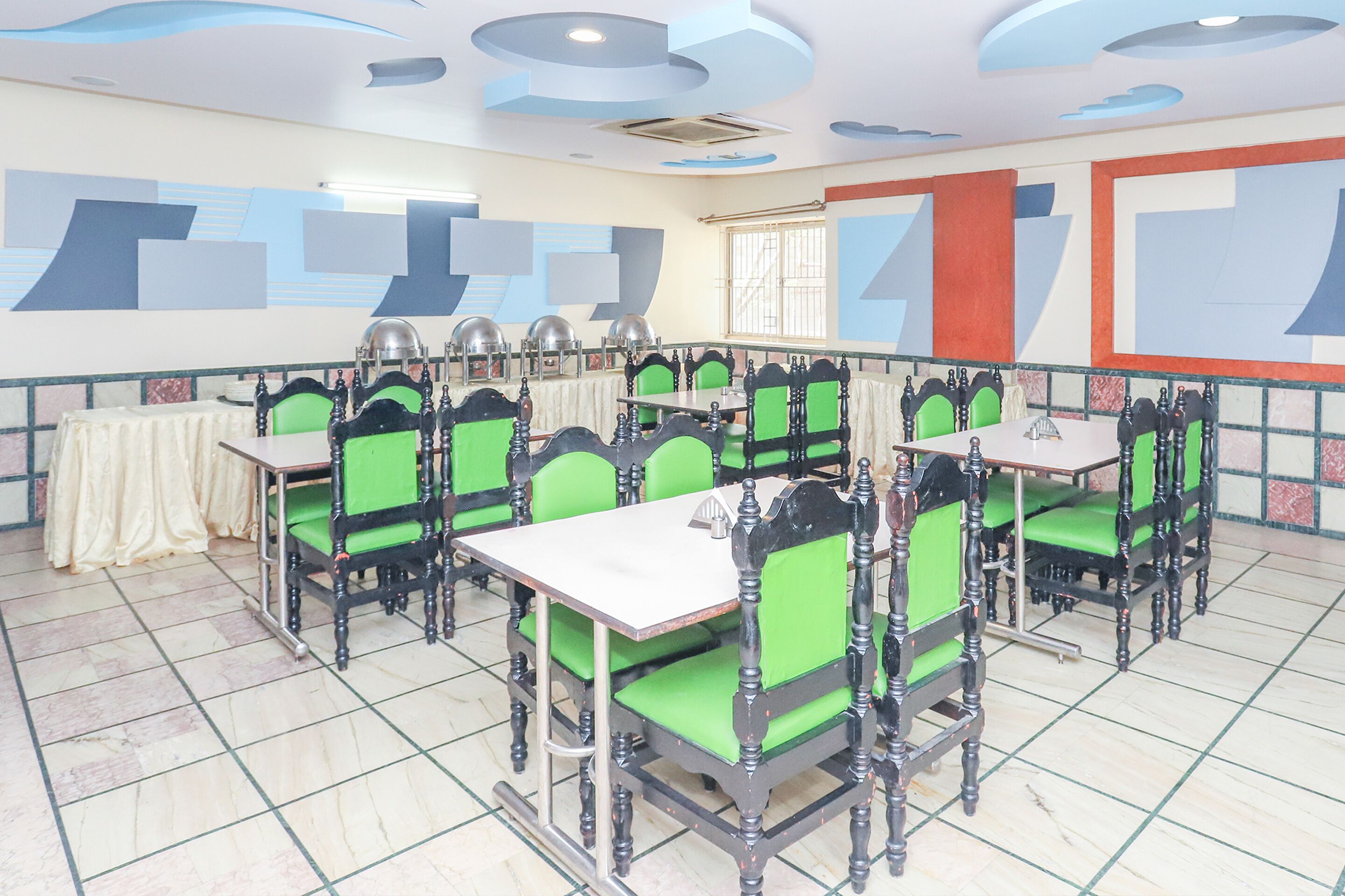 A dining area with green cushioned chairs and white tables, arranged in a semi-circular layout.