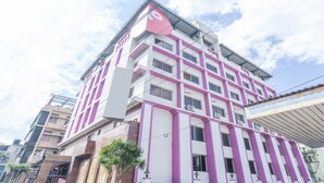 A multi-story building with a distinct pink and white color scheme, featuring a prominent logo on the facade. - OYO 4439 Aura Inn (Bengaluru)