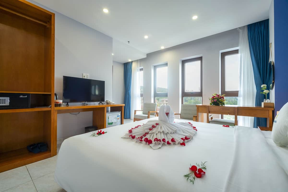 Habitación de hotel con una cama grande, televisión, escritorio y vistas al exterior.