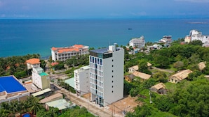 A coastal cityscape with a mix of modern and traditional buildings, a clear view of the sea, and a prominent white building with a blue facade. - Stellar Hotel (Phu Quoc)
