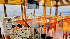 A dining area with a view of the city, tables with chairs, and a large pot on the table. - Stellar Hotel (Phu Quoc)