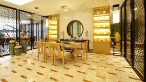 A dining area with a wooden table and chairs, a chandelier, and a decorative mirror. - Zijing International Hotel (Enshi)