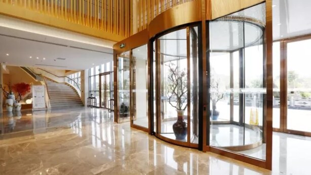 A modern lobby with a curved glass entrance, a marble floor, and a staircase leading to an upper level. - Zijing International Hotel (Enshi)