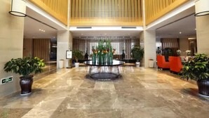 A spacious lobby with a central water feature, potted plants, and modern seating areas. - Zijing International Hotel (Enshi)