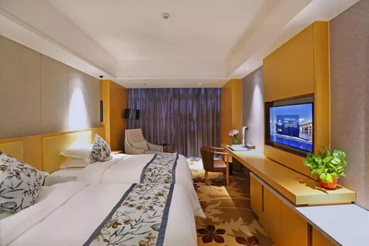 Ett hotellrum med en stor säng, ett skrivbord, en stol och en tv.
