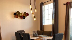 Un comedor con una mesa y sillas de madera, una araña y una lámpara fijada a la pared.