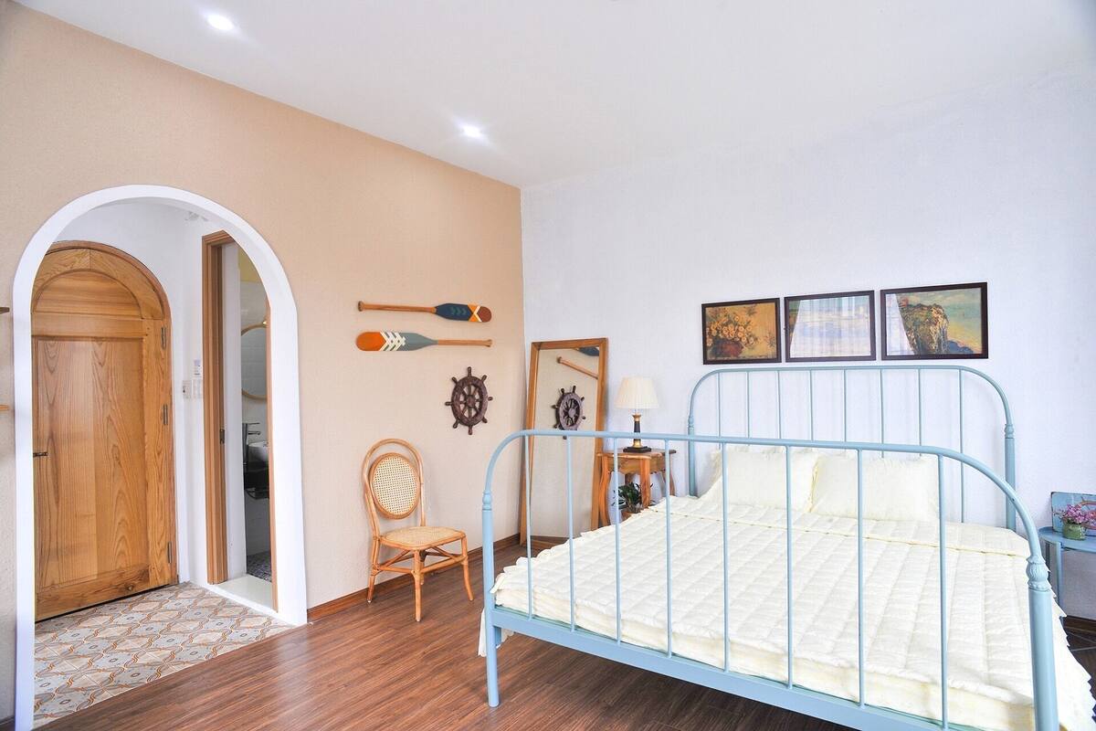 A bedroom with a bed, wooden wardrobe, arched doorway, and wall-mounted decorations.