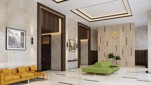Een moderne lobby met een groene bank, een gele bank en een houten accentmuur met een geometrisch ontwerp.