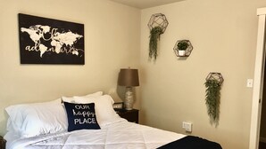Ein Schlafzimmer mit einem Bett, einer Weltkarte als Wandbild, einer Lampe und zwei Wandgefäßen.
