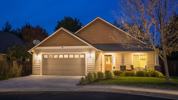 Ein eingeschossiges Haus mit Garage, einer Veranda und einem kleinen Garten.