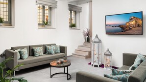 A spacious living area with a sofa, a round coffee table, and a painting of a coastal scene. - Boutique Home-Splantzia-Roof Garden-2min Harbor (Chania)