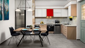 A modern kitchen with a dining area, featuring a wooden table, black chairs, a stainless steel refrigerator, and a red cabinet. - Boutique Home-Splantzia-Roof Garden-2min Harbor (Chania)