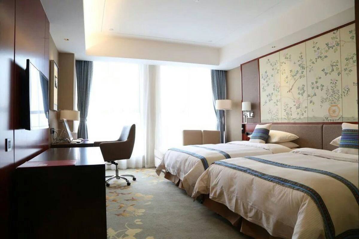 A hotel room with two beds, a desk, and a chair.