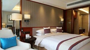 Quarto de hotel com uma cama grande, um sofá, uma mesa de cabeceira e um espelho.