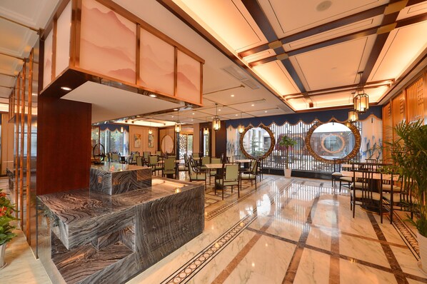 A spacious lobby with a marble reception desk, multiple seating areas, and a large circular window. - Jingcui Huanyi Hotel (Wuhan)