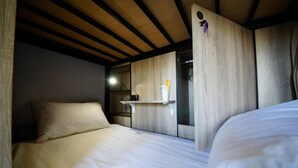 Une chambre avec un lit, une étagère contenant des articles de toilette et un plafond en bois.