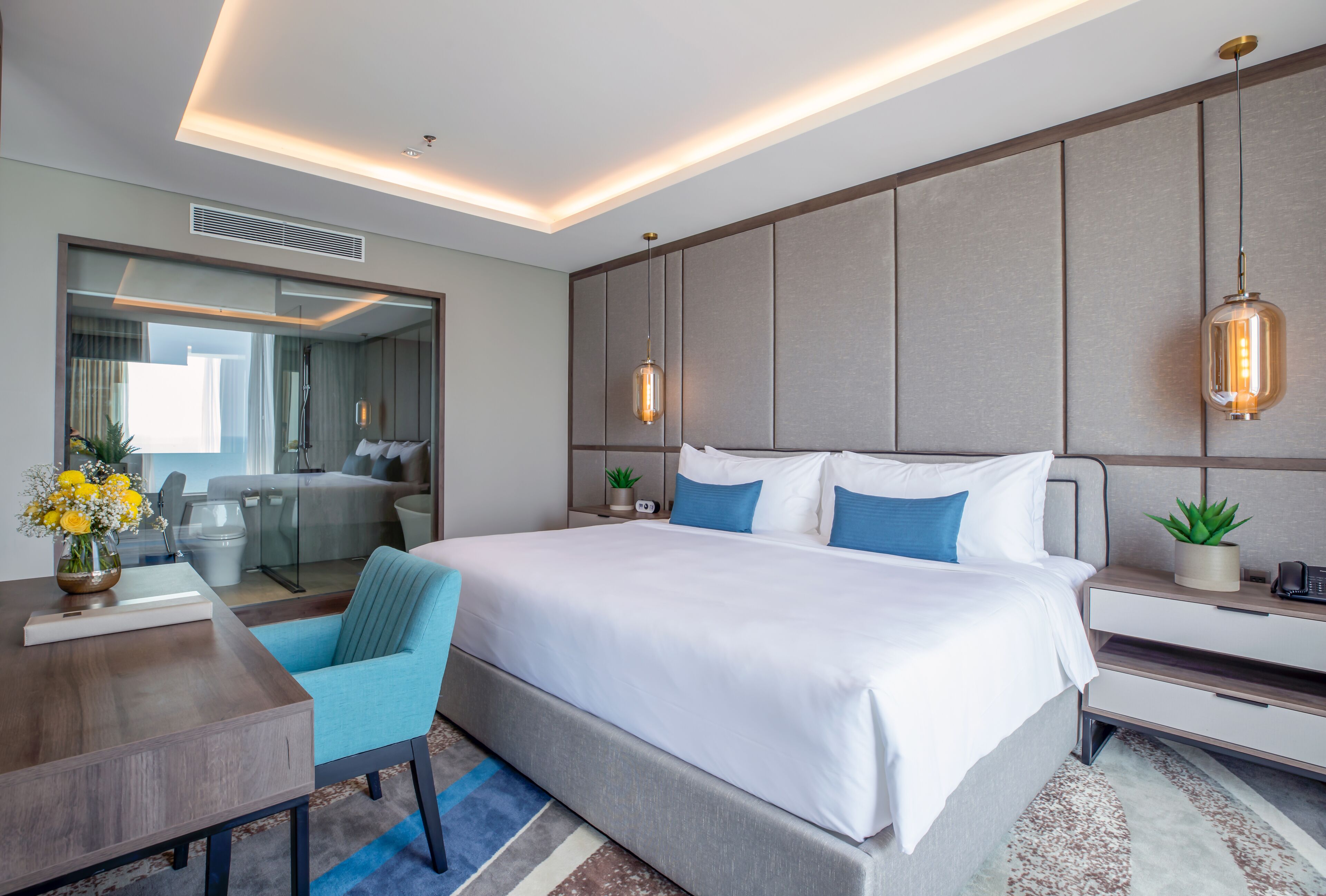 A modern hotel room with a large bed, bedside tables, a desk, and a chair.