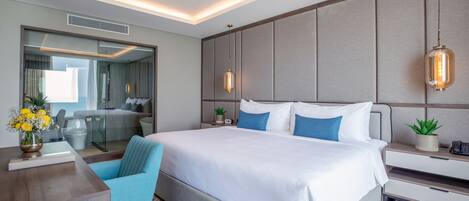A modern hotel room with a large bed, bedside tables, a desk, and a chair.