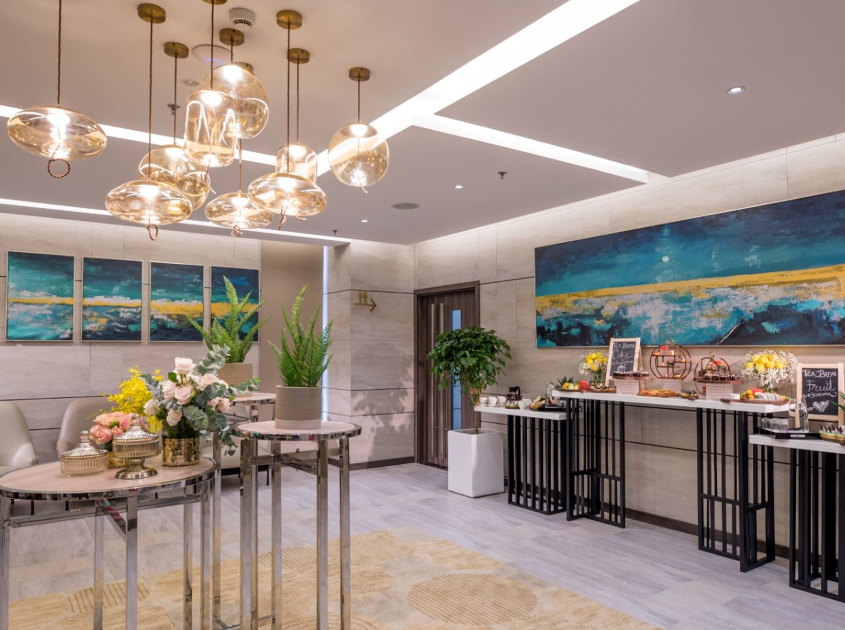 A modern hotel lobby with a reception desk, seating area, and artwork on the walls.