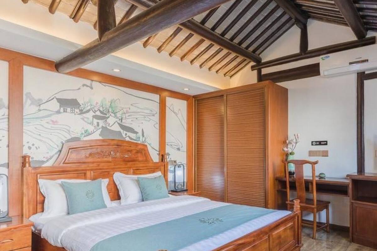 A bedroom with a wooden bed, a desk, and a chair.