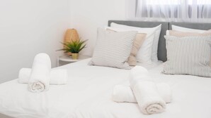 A neatly made bed with rolled white towels, a striped pillow, and a small potted plant on the nightstand. - Dov Garden apartment with private pool (Tiberias)