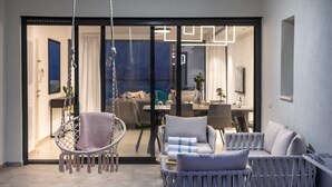 A modern living room with a hanging chair, a sofa, and a dining area visible through a glass door. - Dov Garden apartment with private pool (Tiberias)