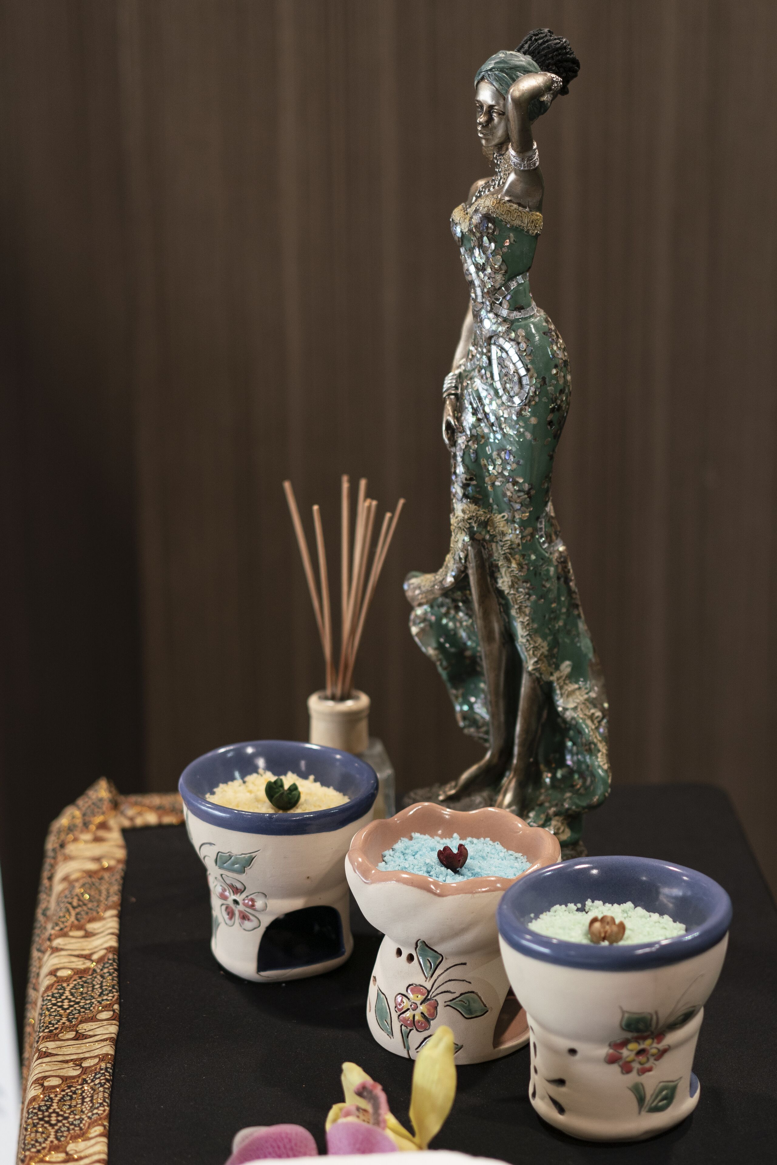 A decorative ceramic figure, three small bowls with colorful contents, and a reed diffuser.