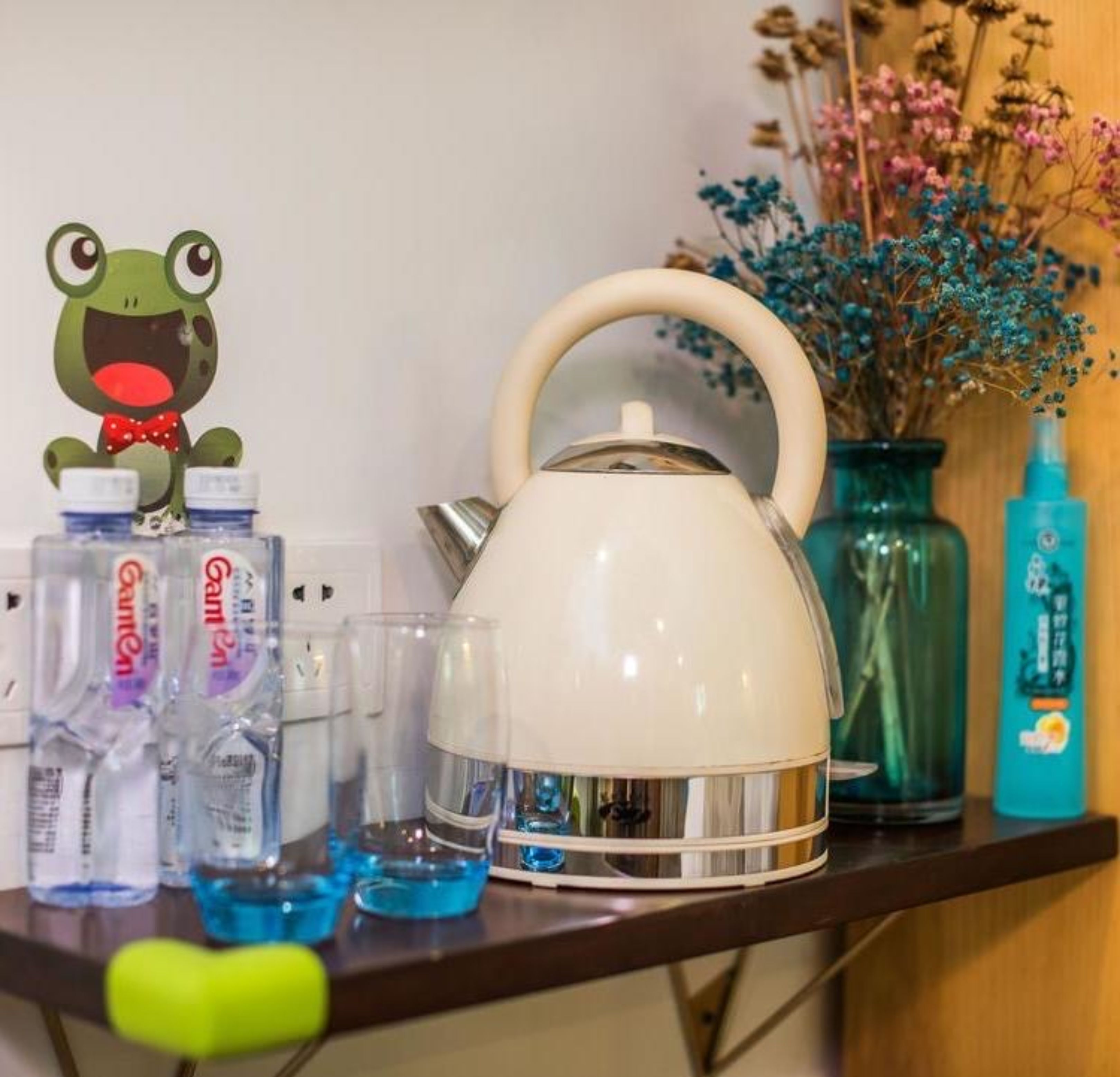 A kitchen counter with a white kettle, clear glasses, and a frog figurine.