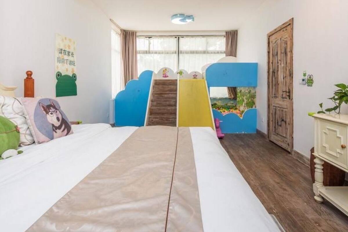 Een kindvriendelijke kamer met stapelbedden, een speelhoek en een groot raam.