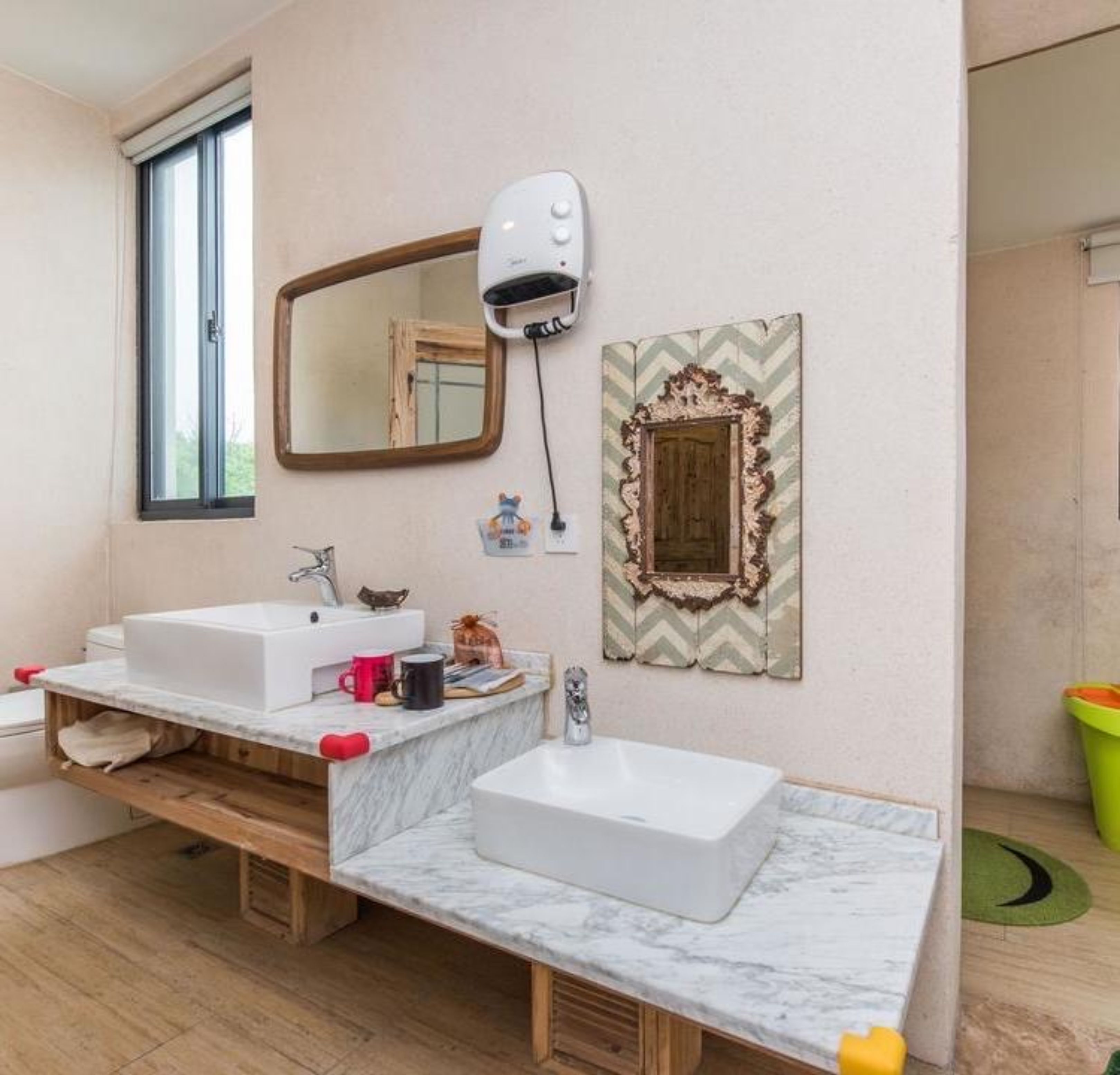 A bathroom with two sinks, a mirror, a hairdryer, and a decorative mirror frame.