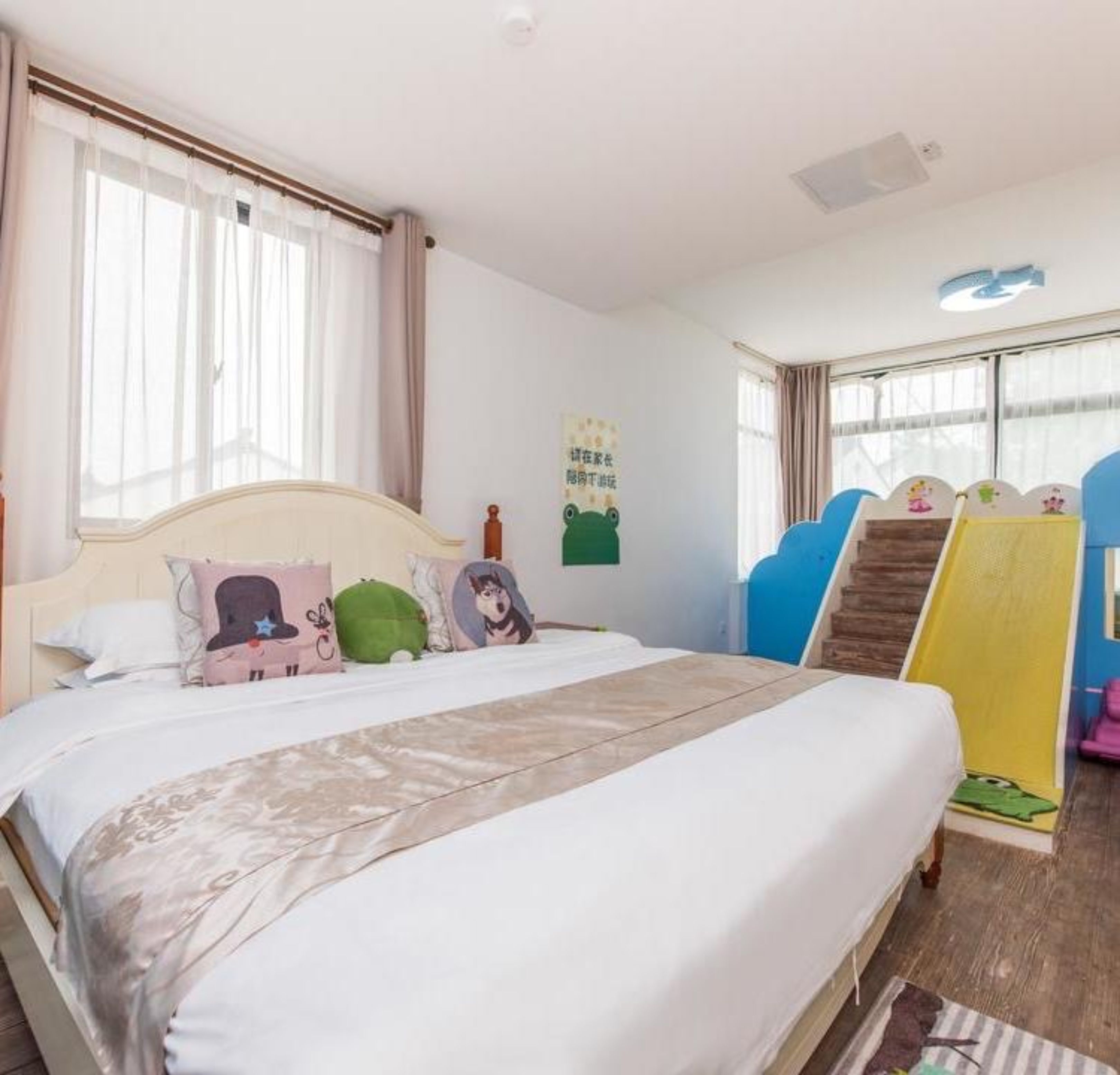 A bedroom with a bed, pillows, a wall decoration, a window, and a toy slide.