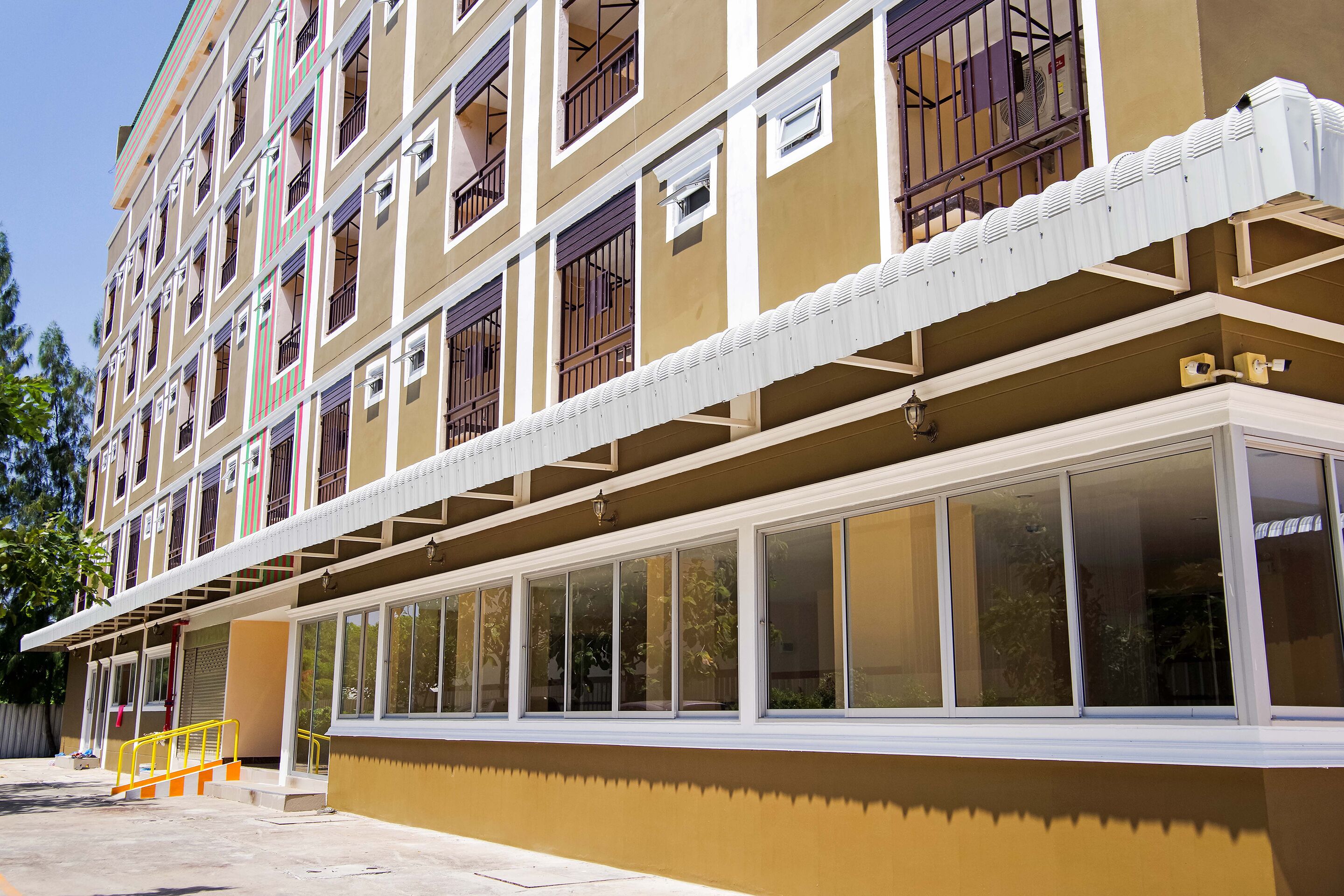 Un edificio de varios pisos con fachada color beige, ventanas amplias y balcones con barandillas de metal.