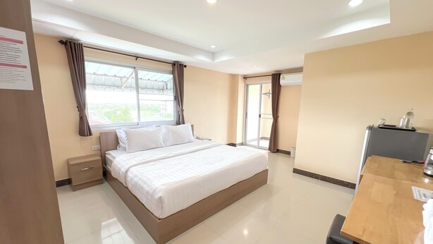 A hotel room with a large bed, a desk, and a view of the outside. - Wises Hotel (Chachoengsao)