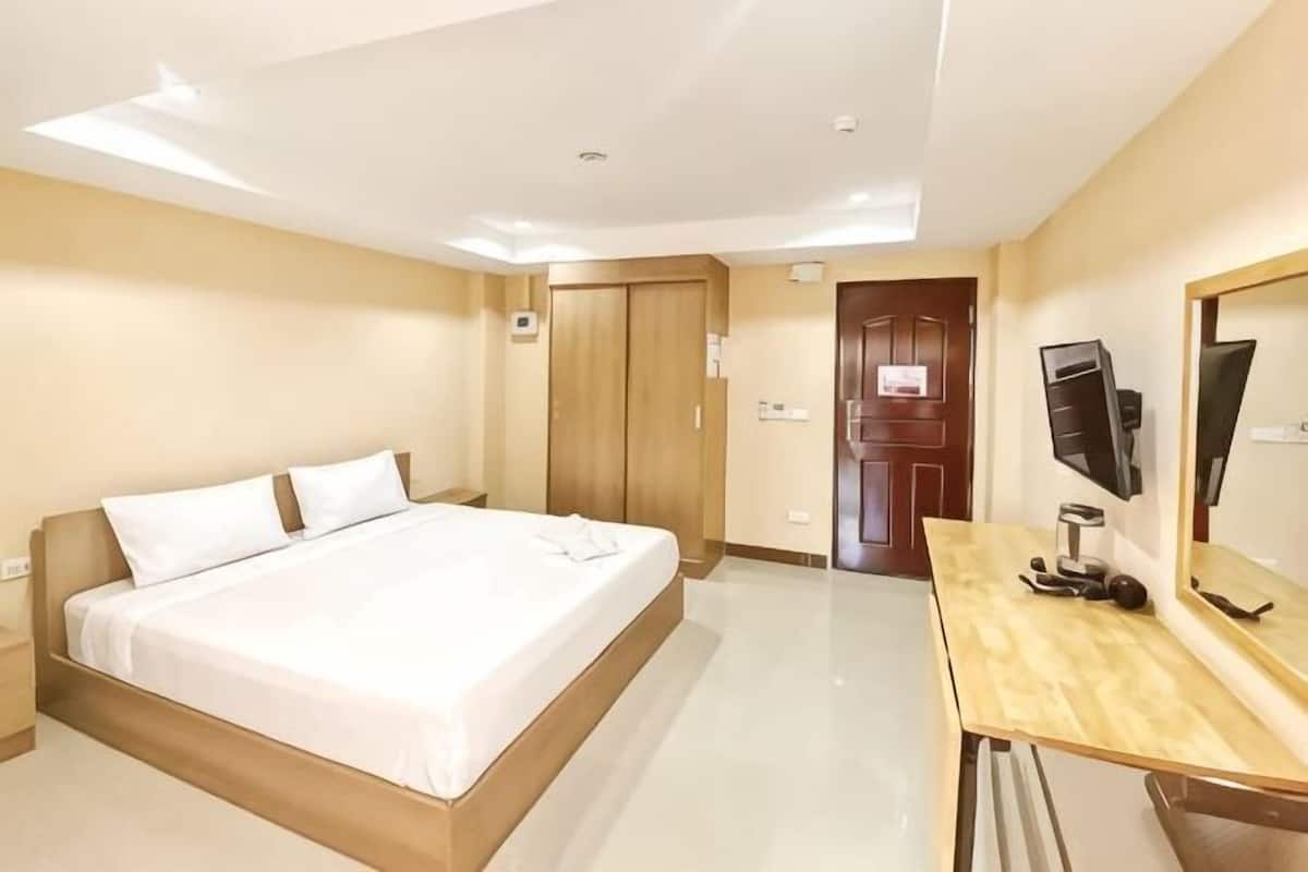 Una habitación de hotel con cama, escritorio, televisor y armario.