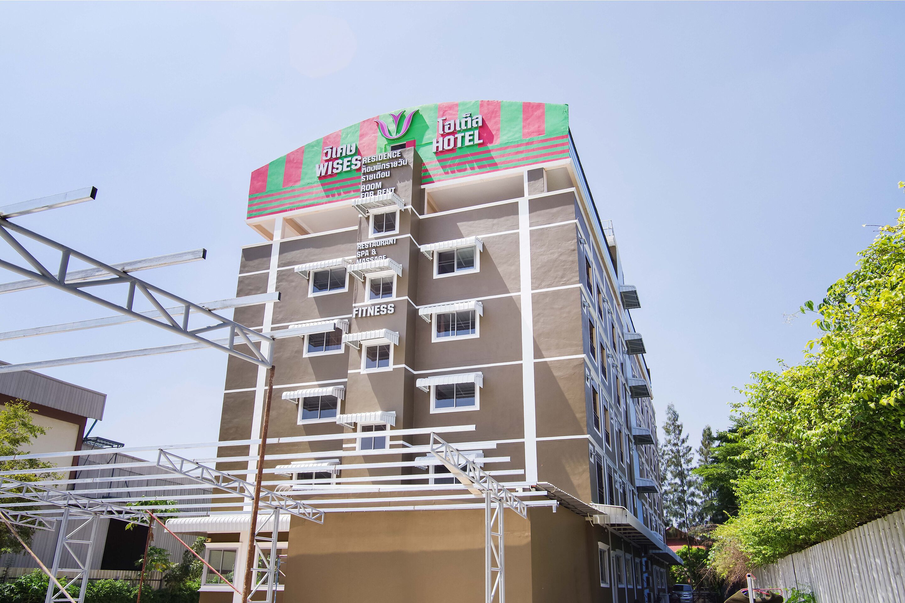 A multi-story hotel with a prominent sign for 'Taina Hotel' and 'Residence'. It has a fitness center and a restaurant on the ground floor.