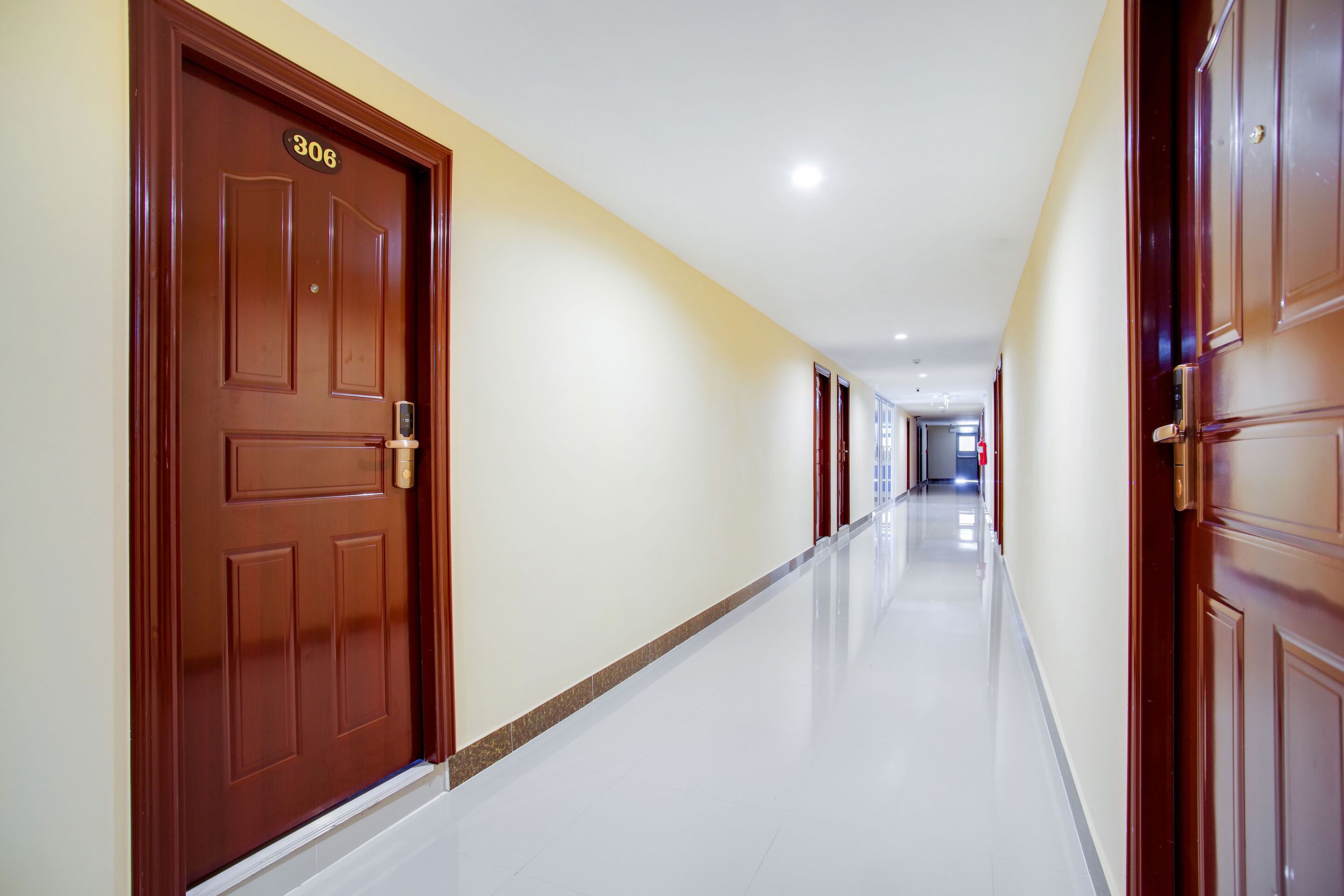 A long, well-lit hallway with wooden doors, each marked with a number.