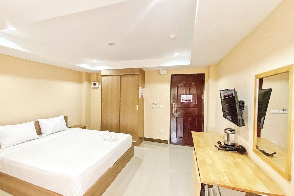 Una habitación de hotel con cama, escritorio, televisor y armario.
