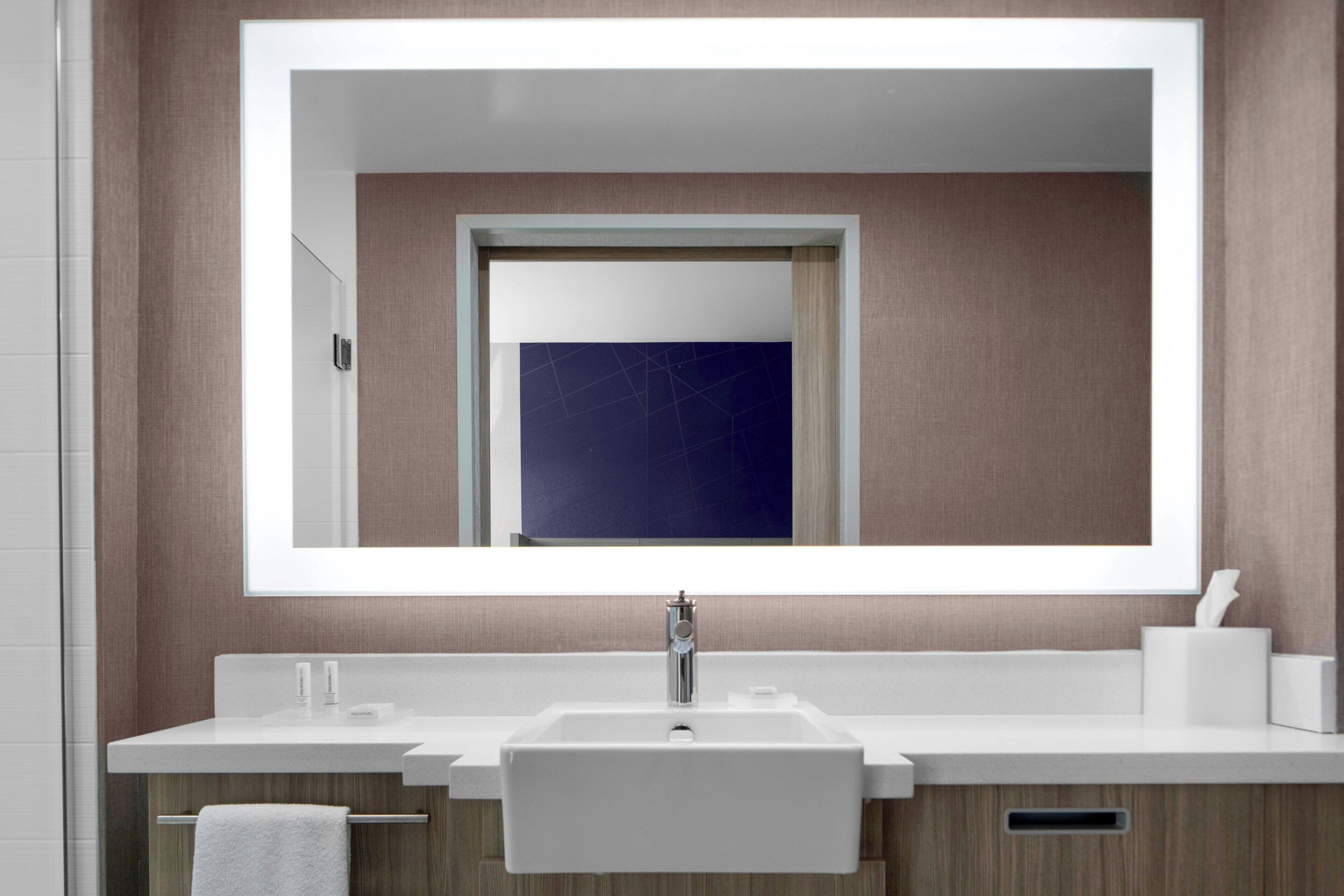 Une salle de bain moderne avec un grand miroir, un lavabo blanc et des meubles en bois.