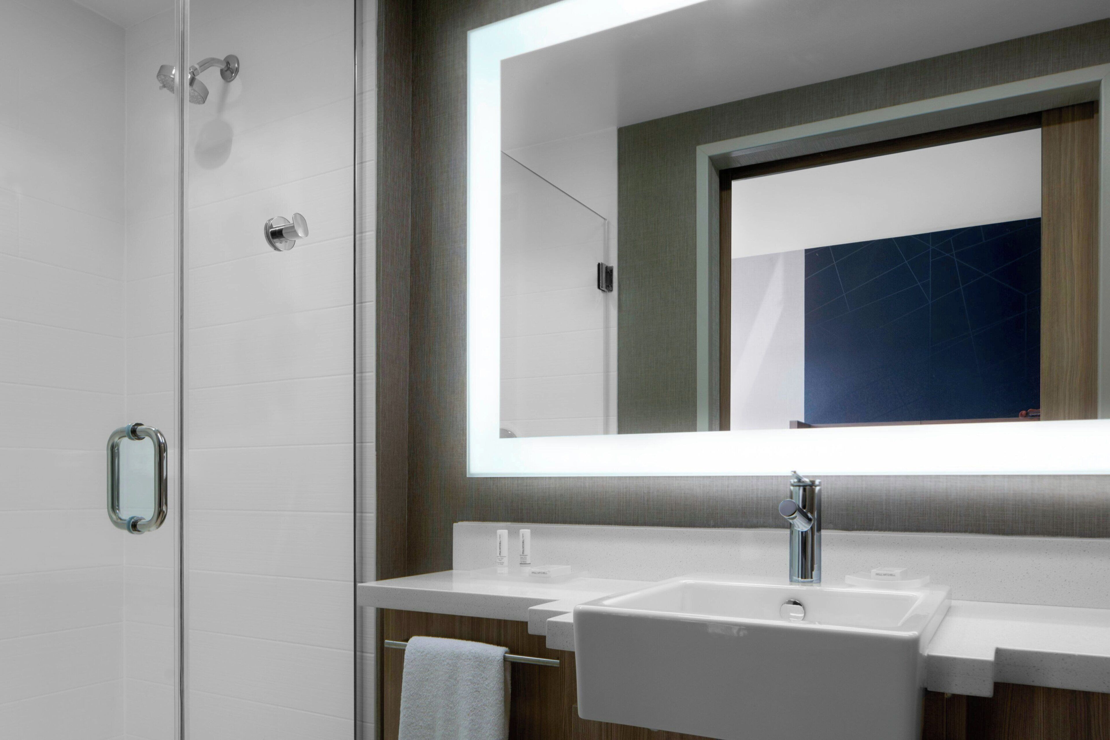 A modern bathroom with a glass shower enclosure, a double sink vanity, and a large mirror above the vanity.