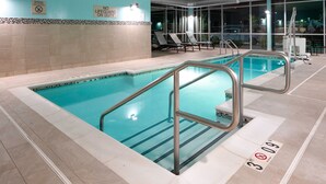 An indoor swimming pool with clear water, metal railings, and lounge chairs. - SpringHill Suites by Marriott Winchester (Winchester)