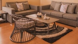 Ein gemütliches Wohnzimmer mit hohen Decken, zwei Sofas, einem Couchtisch und einem einzigartigen Sessel.